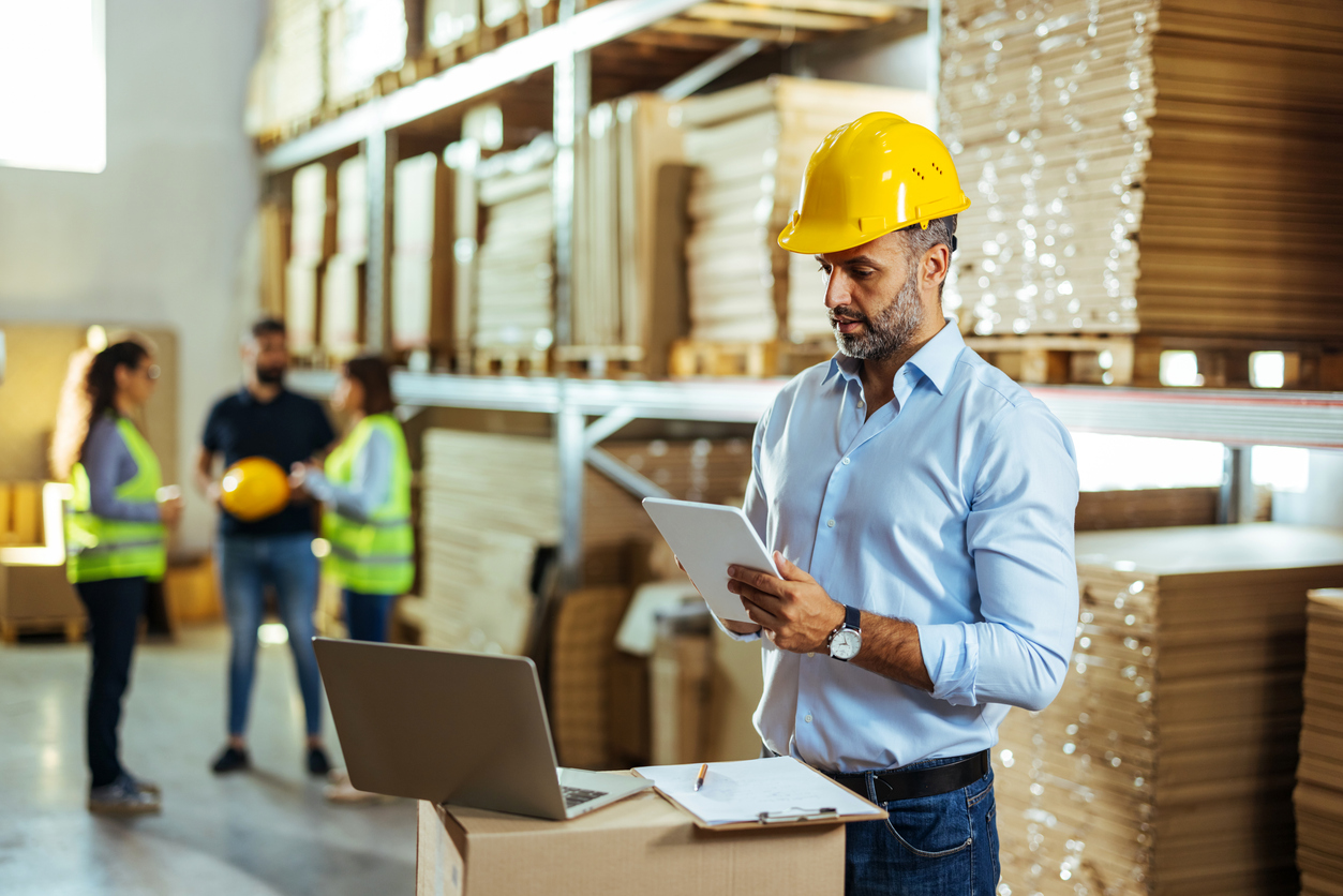 Warehouse manager working process checking the package with a tablet in a large distribution center