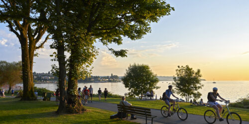 Vancouver, B.C., Canada - July 18, 2012: Young couple cycling, others walking or jogging late afternoon and enjoying the sunset at Stanley Park